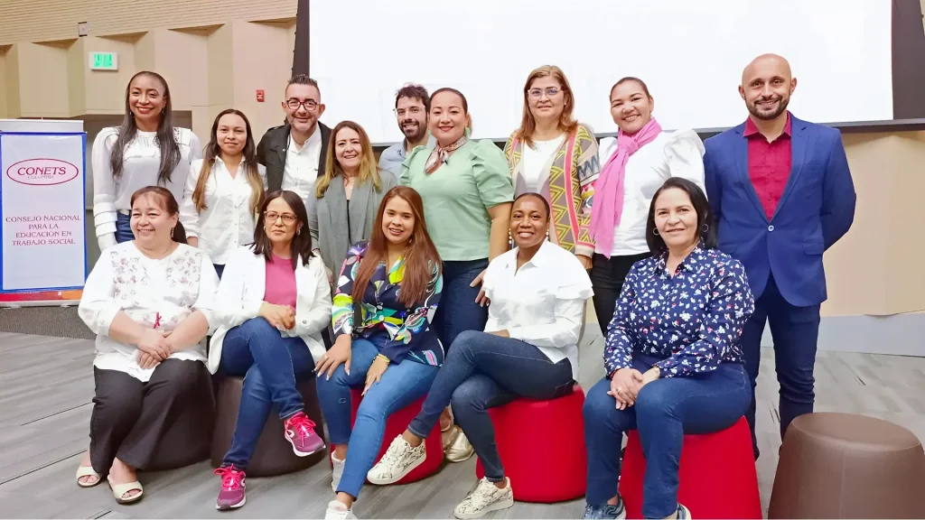 Un grupo de hombres y mujeres posando juntos en un evento en un interior con un cartel de "CONETS" al fondo.