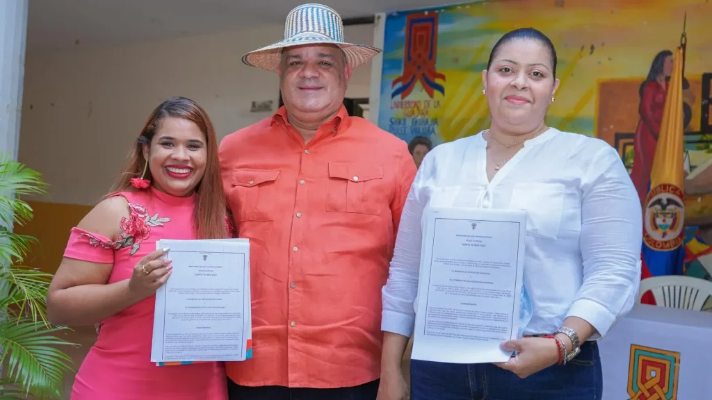 Un hombre y dos mujeres posando con certificados. El hombre lleva un sombrero vueltiao.