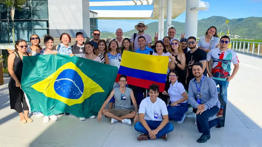 Un grupo de personas posando al aire libre, con una bandera de Brasil y otra de Colombia.