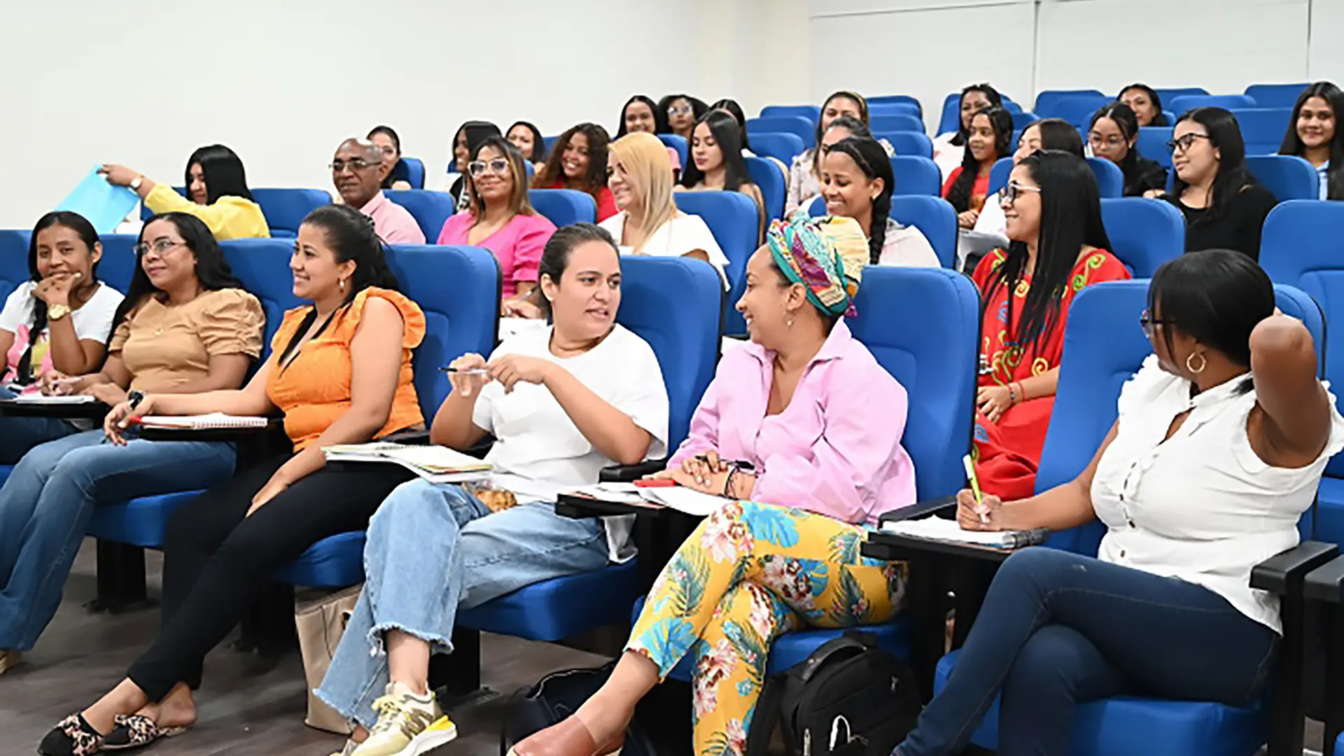 Un grupo de personas sentadas en un auditorio durante una clase.