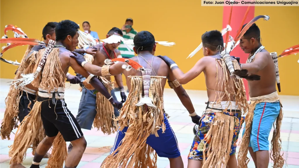 Seis hombres indígenas danzando en las instalaciones de la Alma Máter
