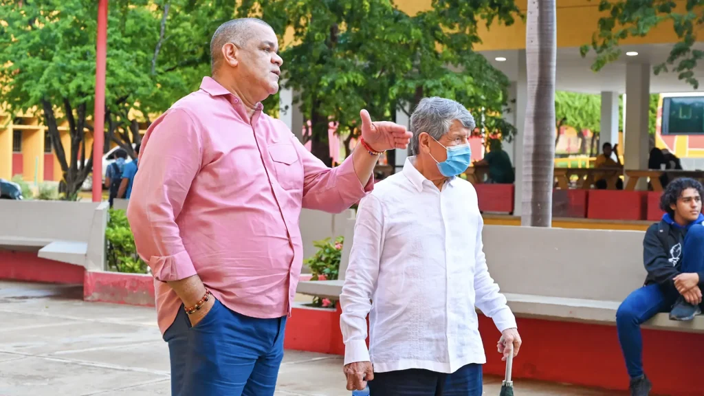 Hombre mayor junto a hombre adulto hablando en el campus universitario.