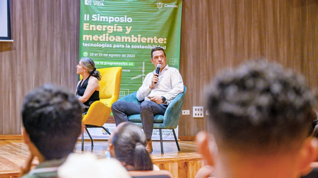 Un hombre con un microfono dirigiendose a una comunidad de estudiantes