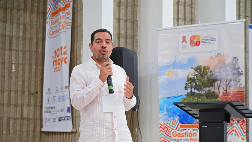 Hombre adulto habla por un micrófono en un auditorio.