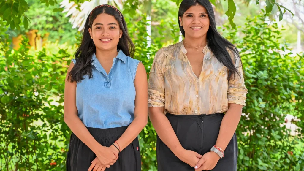 Dos mujeres jóvenes posan para una foto en un exterior.