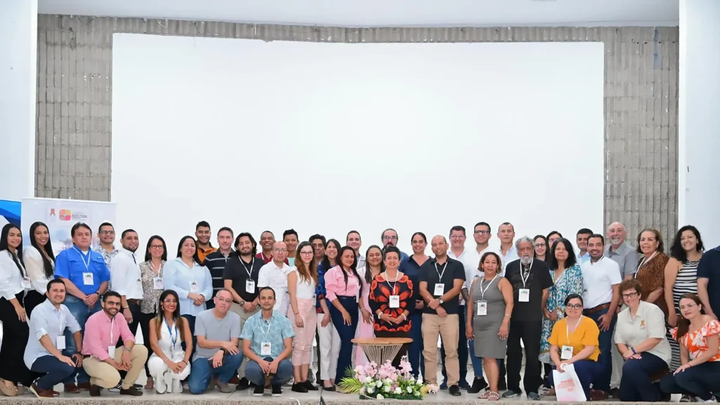 Grupo grande de personas posa para una foto al interior de un auditorio.