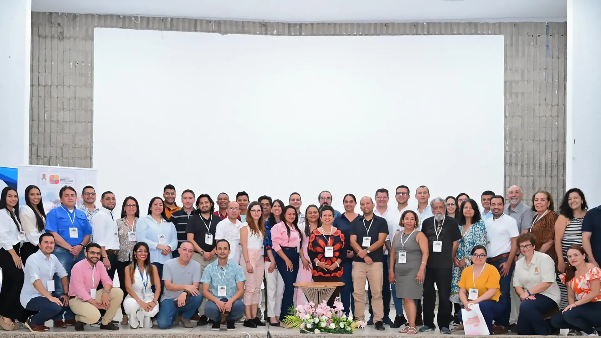 Grupo grande de personas posa para una foto al interior de un auditorio.