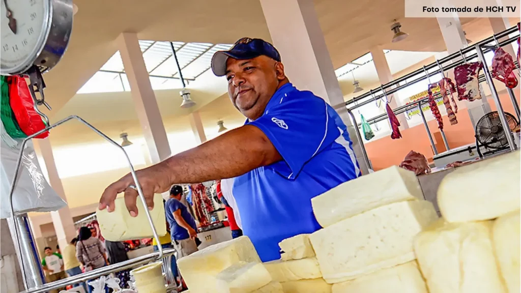 Hombre adulto pesando un bloque de queso.
