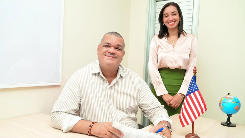 Hombre y mujer adultos frente a un escritorio firmando un papel. 
