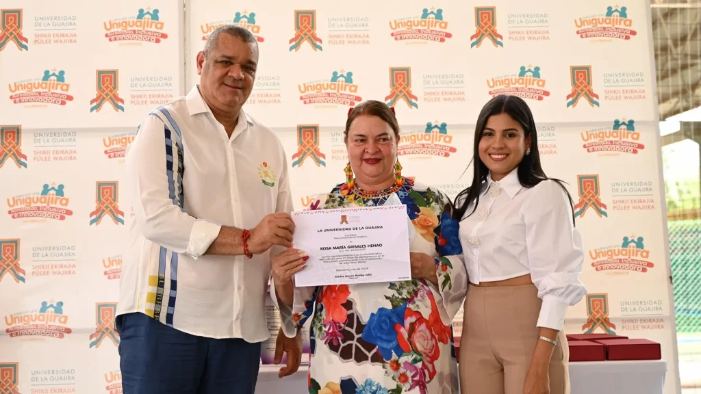 Tres persona en una fotografía, la del medio sostiene un certificado otorgado por quienes la acompañan