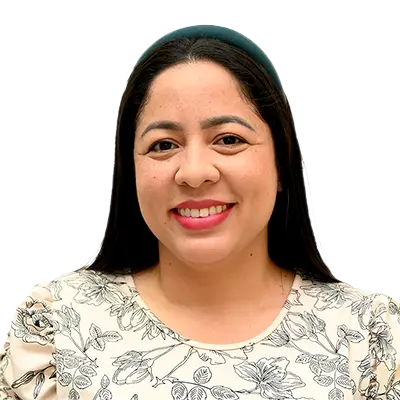 Malka Irina Moreno Fernández Directora del programa de agroecología.Una mujer de cabello largo y liso, suelto, lleva una diadema verde oscuro. Viste una blusa clara con estampado floral en tonos oscuros y sonríe mientras mira a la cámara, sobre un fondo completamente blanco.