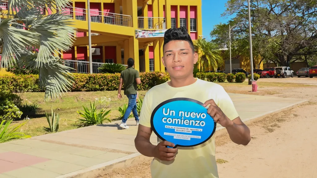 Estudiante nuevo en la sede Fonseca de la Universidad de La Guajira, sosteniendo un cartel que dice “Un nuevo comienzo”.