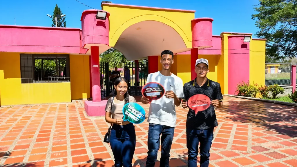 Grupo de cuatro estudiantes nuevos en la sede Fonseca de la Universidad de La Guajira, sosteniendo carteles de bienvenida e inclusión.