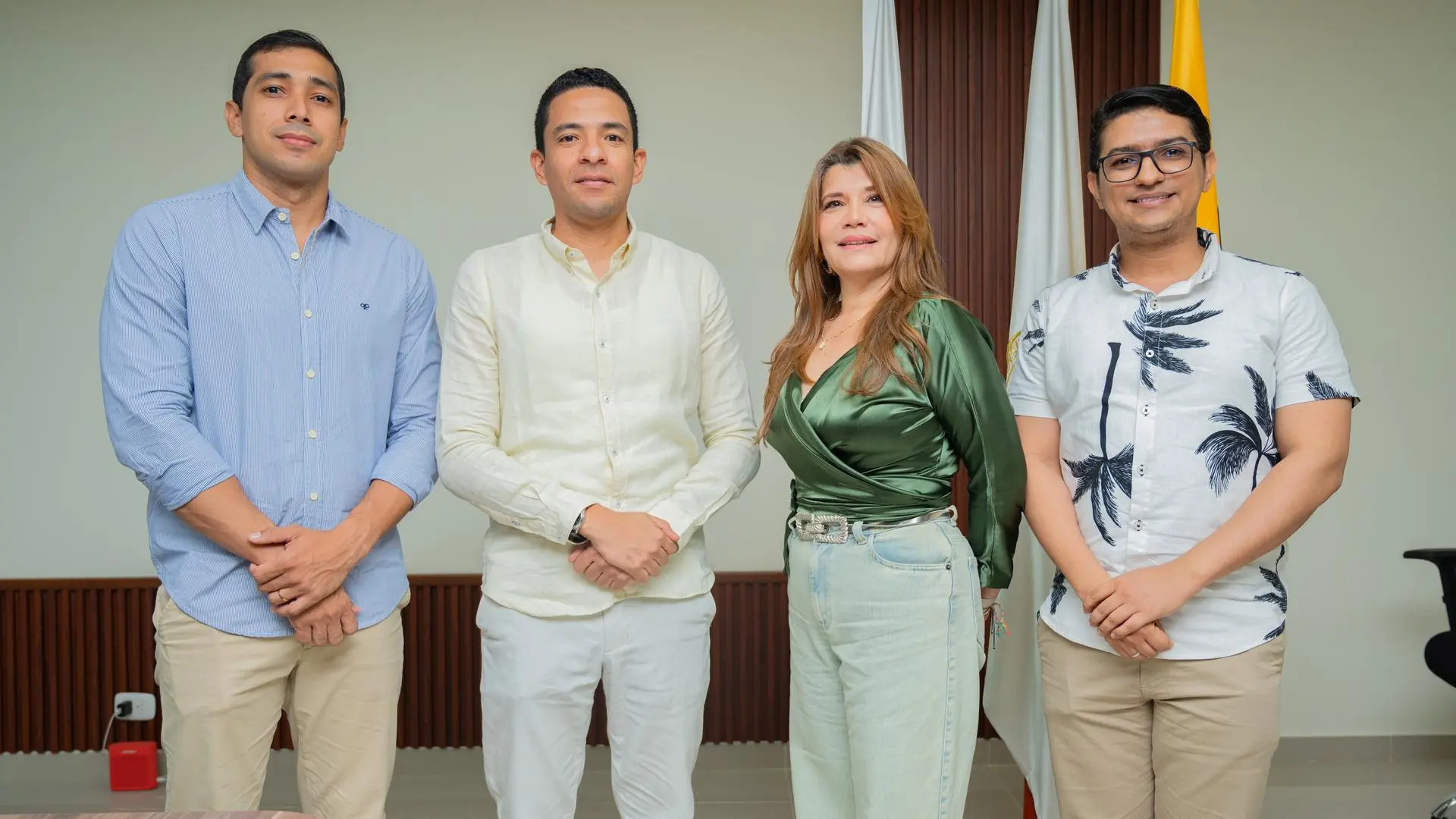 Los docentes Andrés Salcedo, Carlos Márquez, Marlyn Aarón y Andrés Solano posan juntos frente a las banderas institucionales durante la presentación de la política de inteligencia artificial de la Universidad de La Guajira.