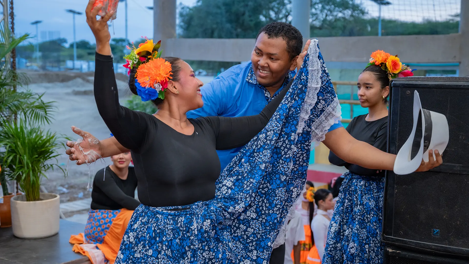 “Pareja de bailarines en traje tradicional azul realizando una danza folclórica, sonrientes y en plena coreografía.”