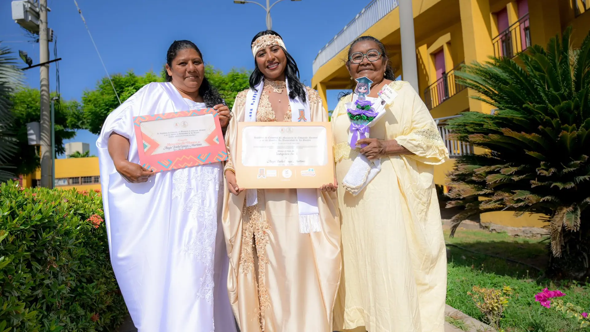 Tres mujeres celebran un logro académico al aire libre, mostrando diplomas en un ambiente de orgullo y acompañamiento familiar.
