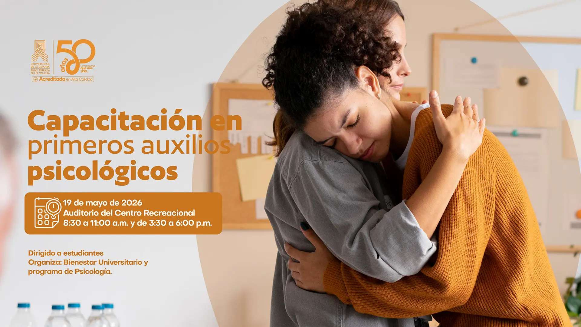Pieza gráfica de la Universidad de La Guajira sobre una capacitación en primeros auxilios psicológicos. En la parte derecha se observa a dos mujeres abrazándose en un espacio interior, representando apoyo emocional y acompañamiento. En la parte izquierda, sobre fondo claro, aparece el título “Capacitación en primeros auxilios psicológicos”. Debajo se informa que la actividad se realizará el 19 de mayo de 2026 en el Auditorio del Centro Recreacional, en horarios de 8:30 a 11:00 a.m. y de 3:30 a 6:00 p.m. También se indica que está dirigida a estudiantes y organizada por Bienestar Universitario y el programa de Psicología. En la esquina superior izquierda se encuentran los logos institucionales de la Universidad de La Guajira y la conmemoración de sus 50 años.