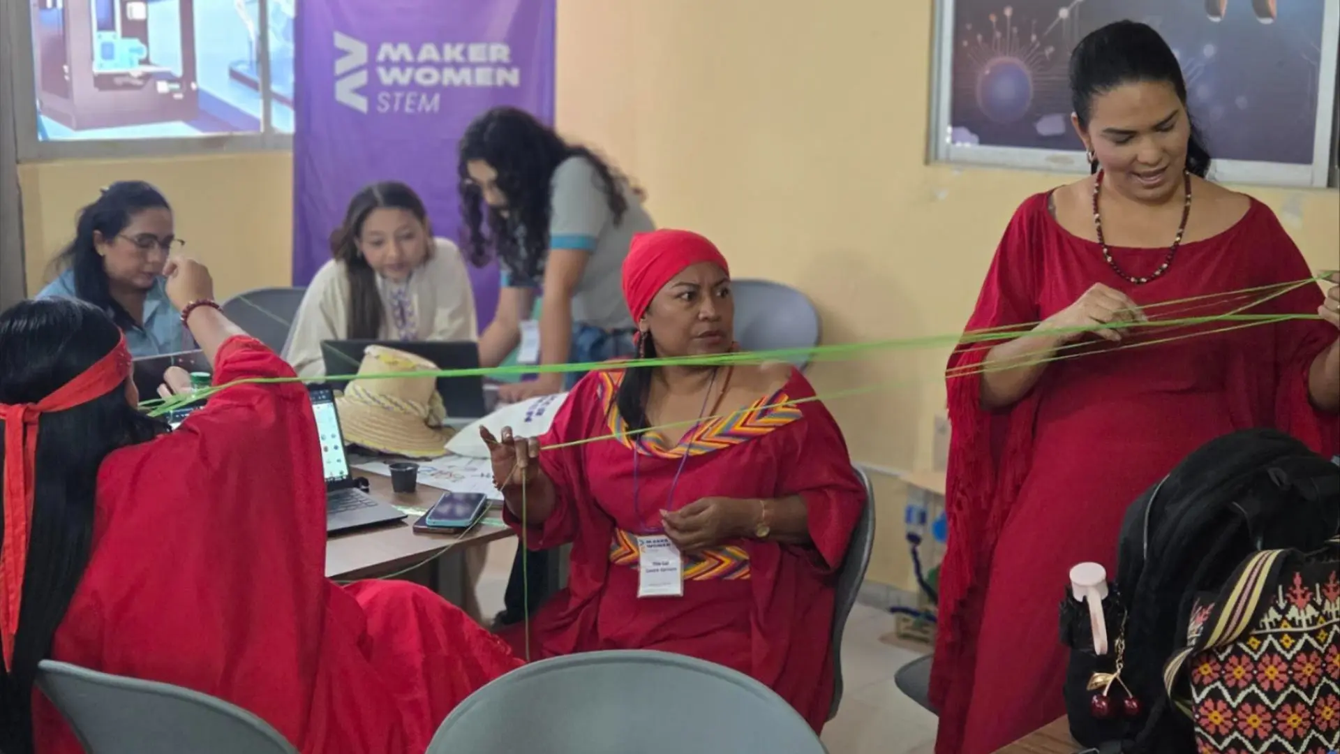 Mujeres participantes de una actividad práctica del programa Maker Women STEM, desarrollando ejercicios de tejido con hilos de colores en un espacio de formación e innovación tecnológica.